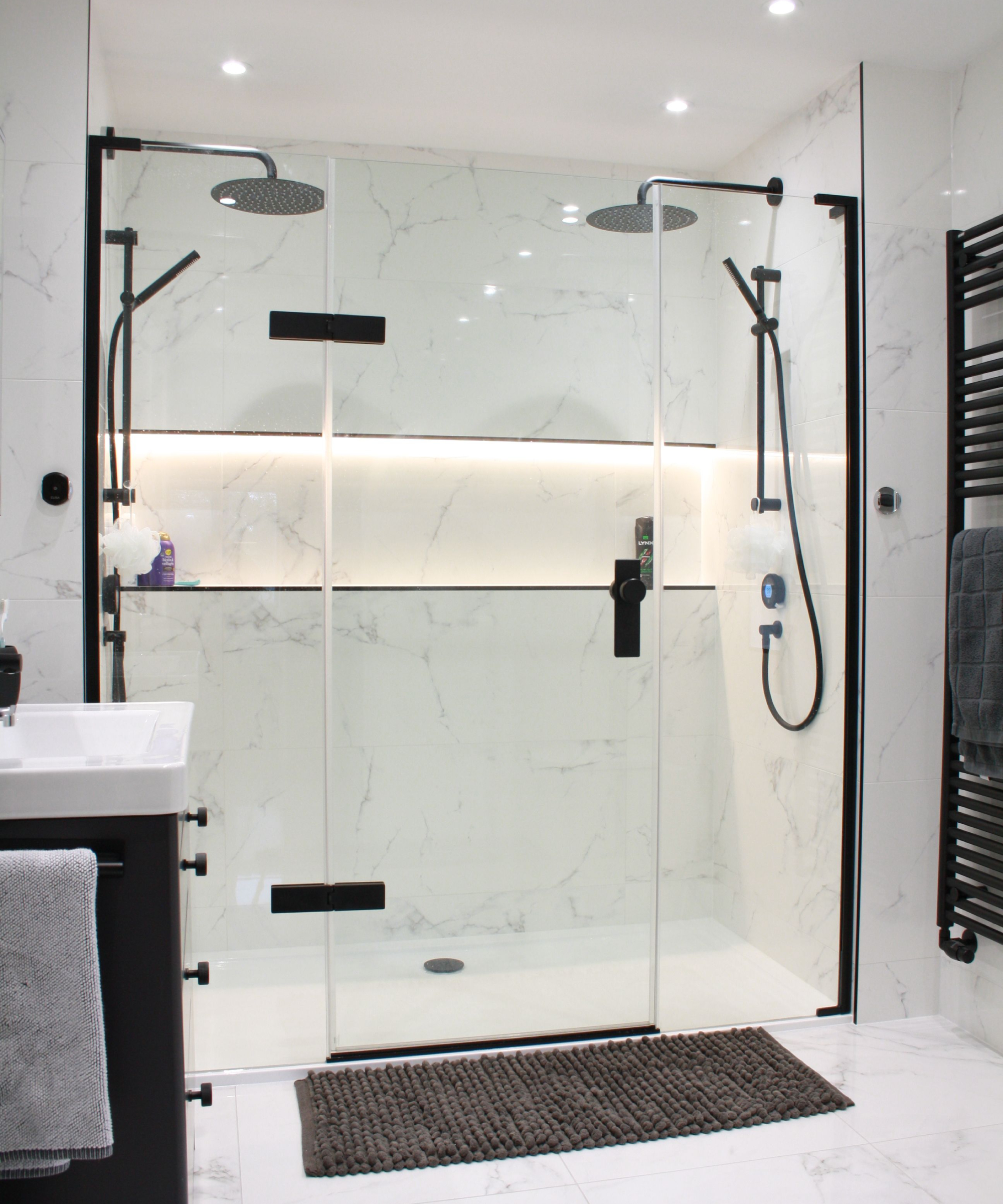 modern bathroom with double shower behing glass doors with LED lit shower niche