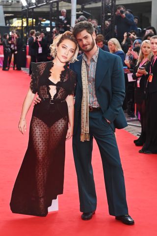 Andrew Garfield posing with a life-sized cardboard cutout of Florence Pugh on the red carpet of We Live In Time's premiere at the 8th BFI London Film Festival at The Royal Festival Hall.