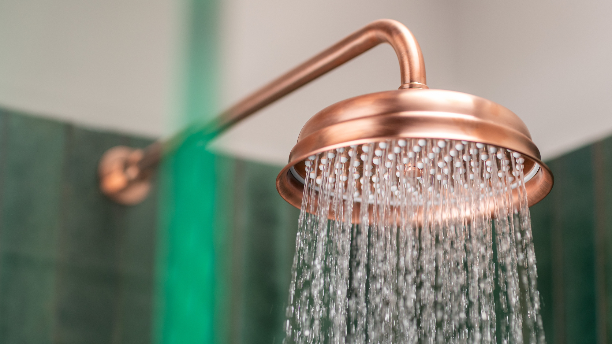 close up shot of copper large round shower head with water running from it