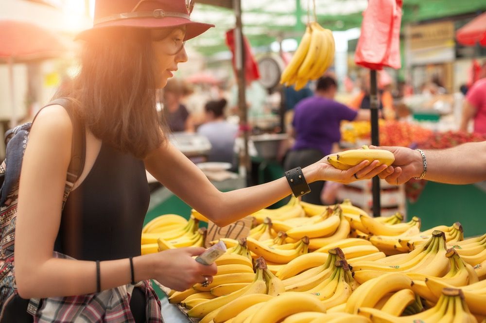 A young woman buying fruits and vegetables at a weekly market. 