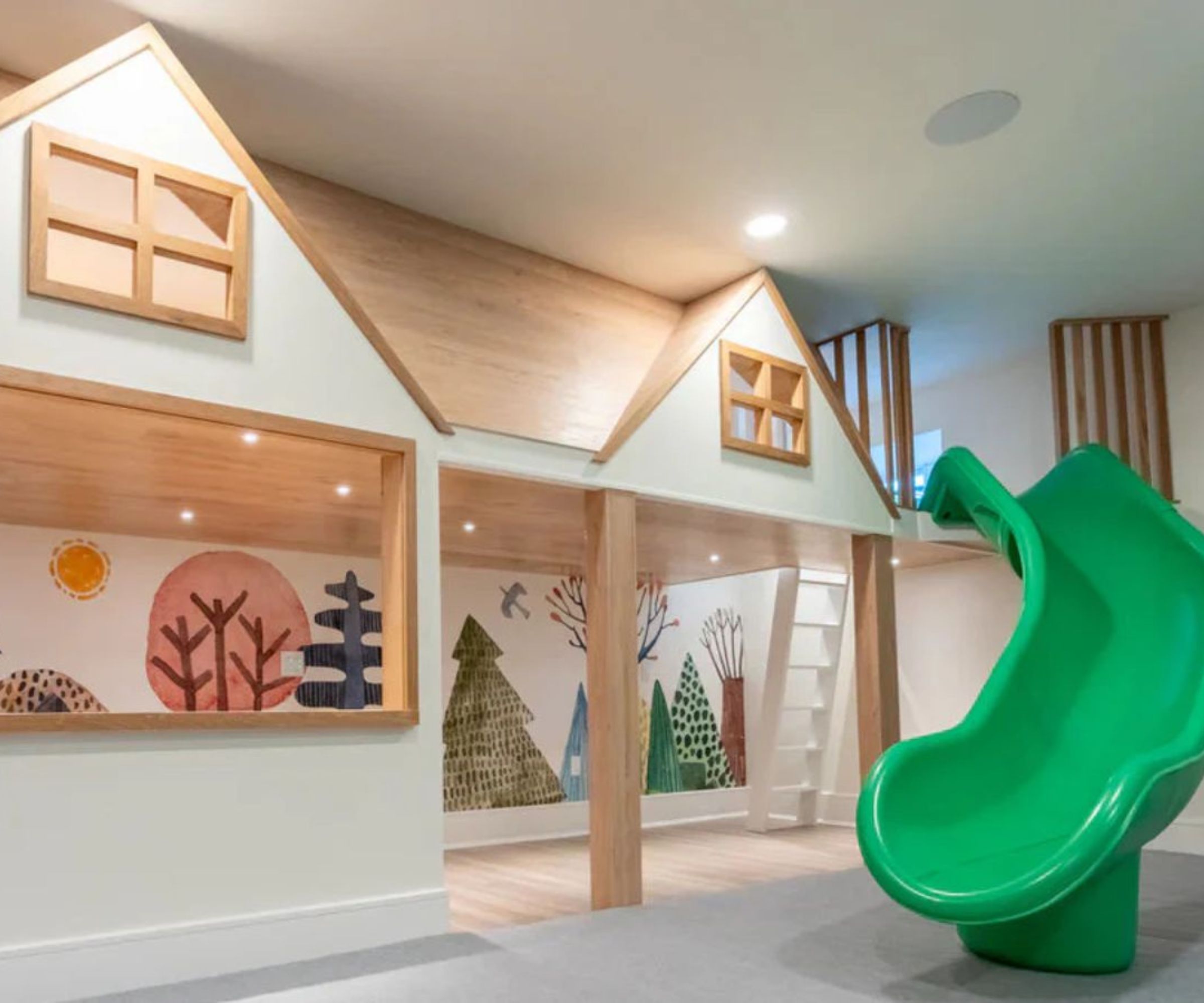 neutral playroom designed with a house within a house play space, a green slide, and colorful painted wall mural