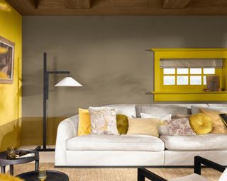 living room with light brown walls, beige sofa, yellow accent wall and yellow window frame