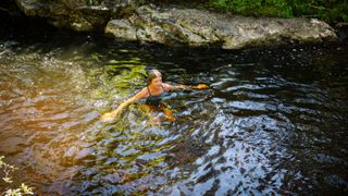 Woman cold water swimming in small lake in swimming costume