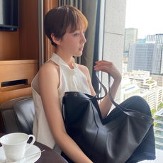 Photo of Reina Triendl wearing white cotton poplin shirt, jeans, and black bag while in Tokyo hotel room.