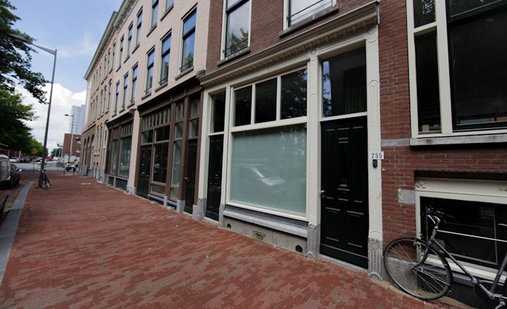 The exterior or a brown brick building with black doors and shutter window. Shades of brown birck walk way 