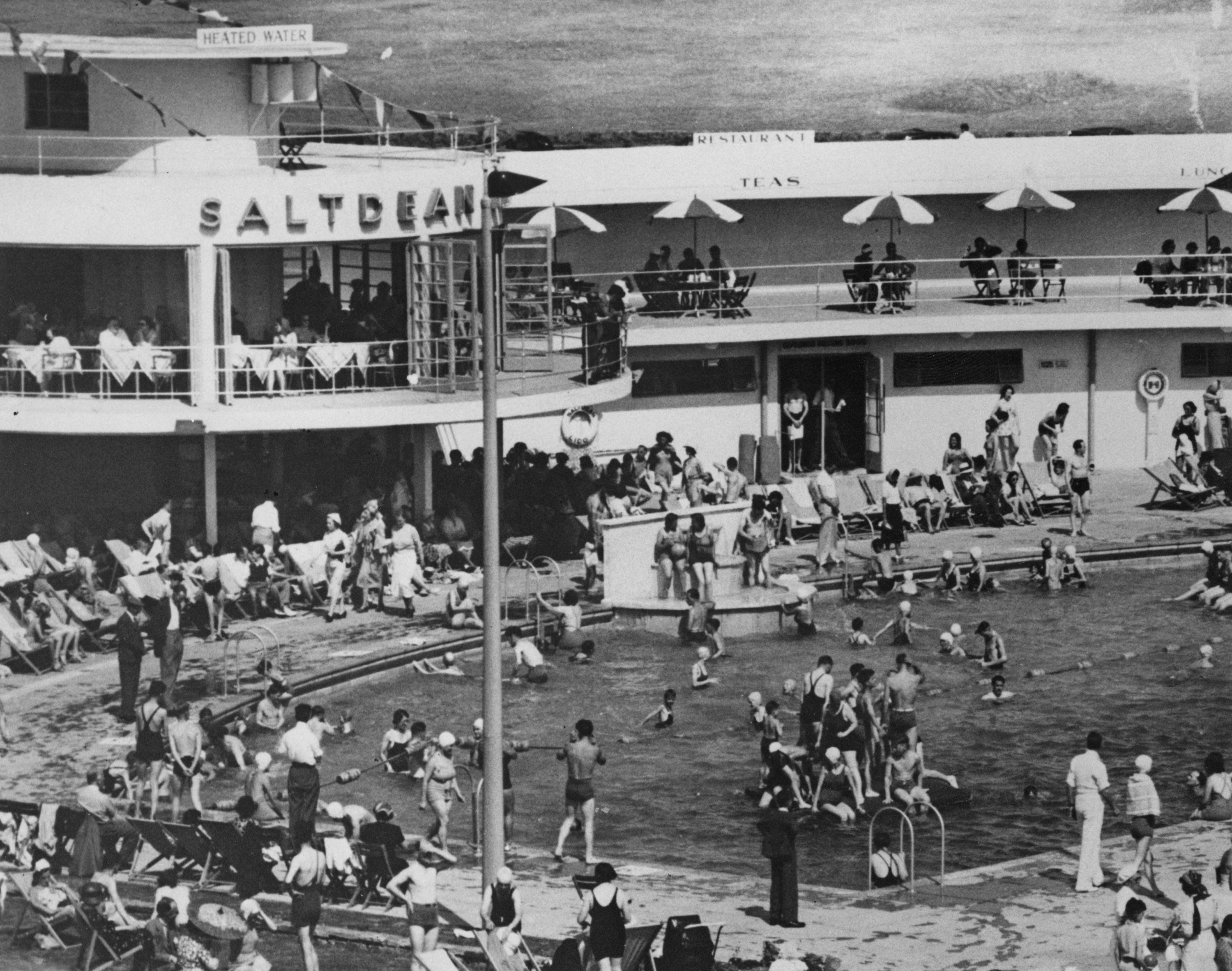 Black and white image of people crowding round an Art Deco lido