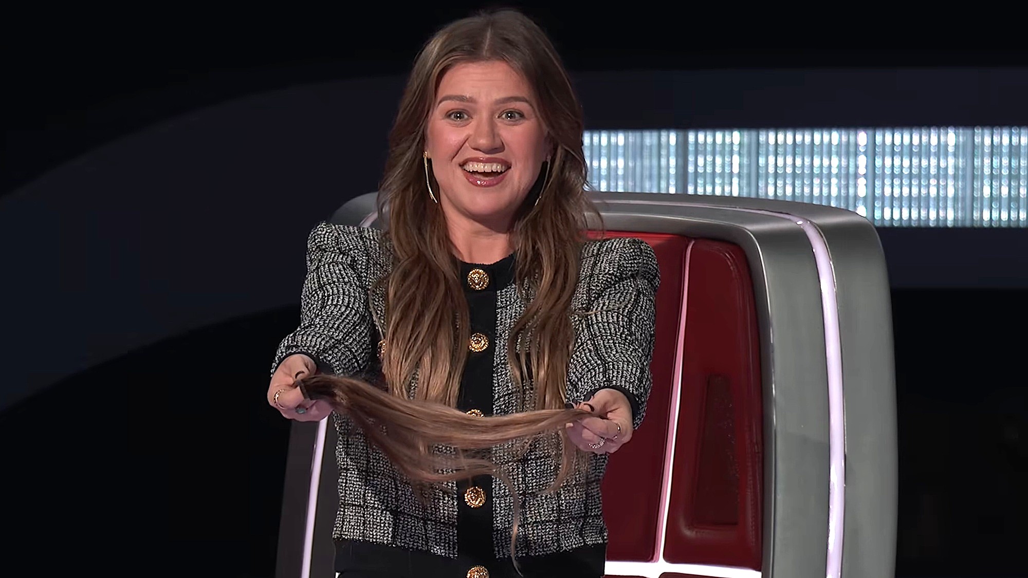 Kelly Clarkson offers one of her hair extensions to an artist on The Voice Season 30.