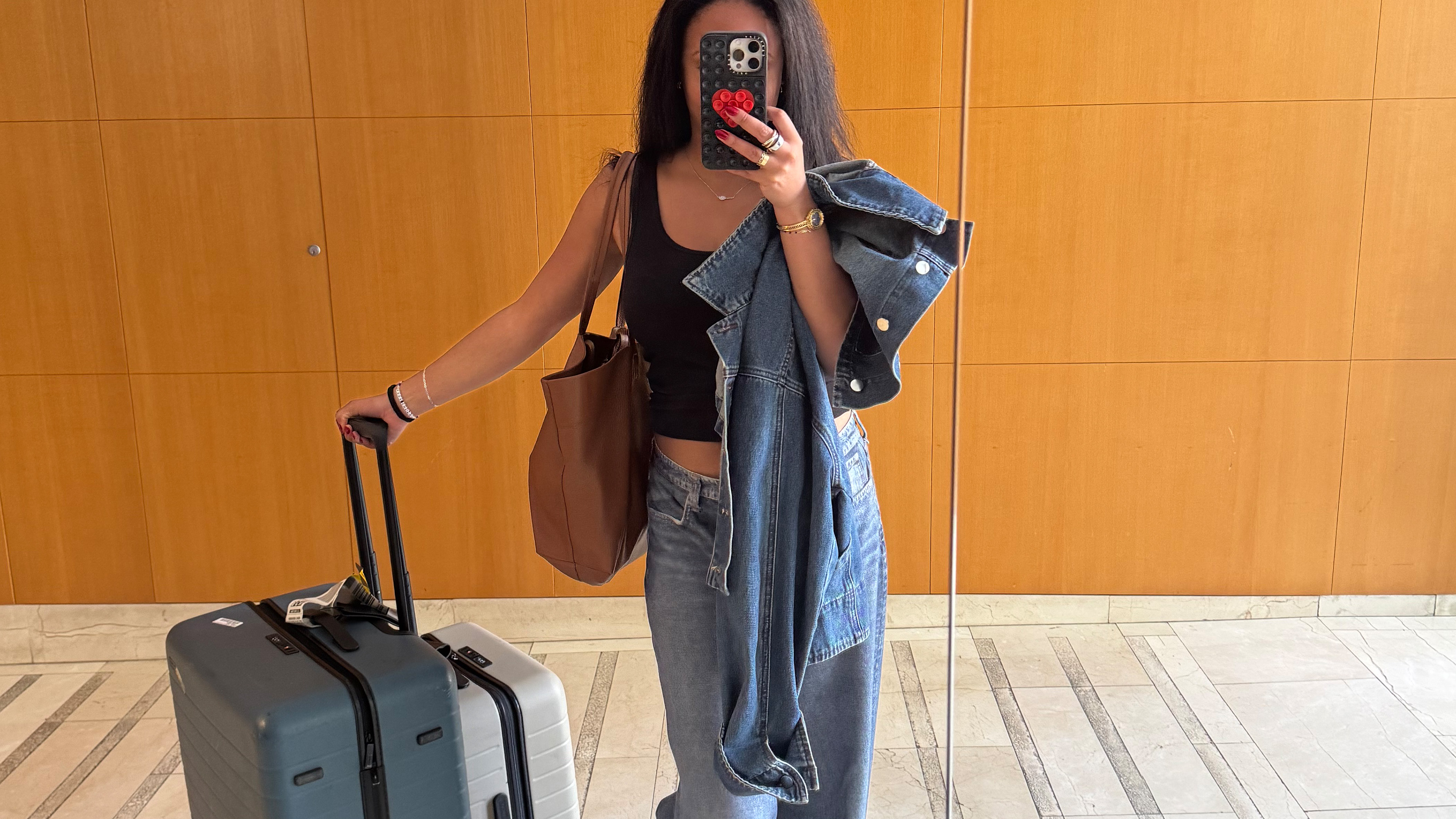 Sierra Mayhew taking a mirror selfie next to two suitcases.