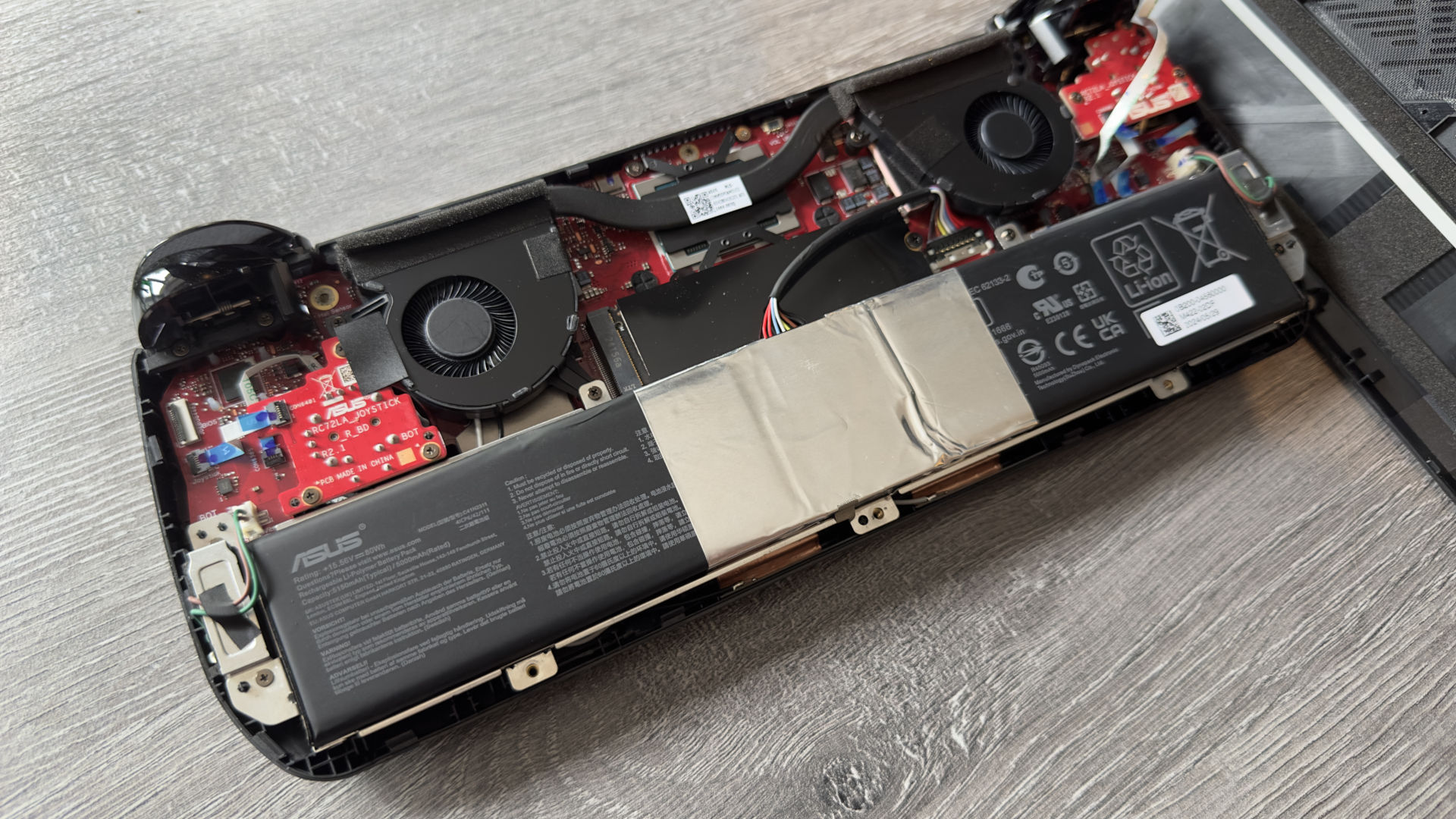 A photo of the interior of an Asus ROG Ally X handheld gaming PC, showing the device's components and layout