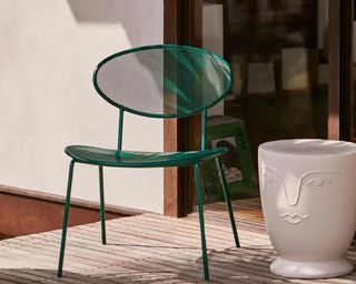 A green Mimi stackable outdoor dining chair with white side table