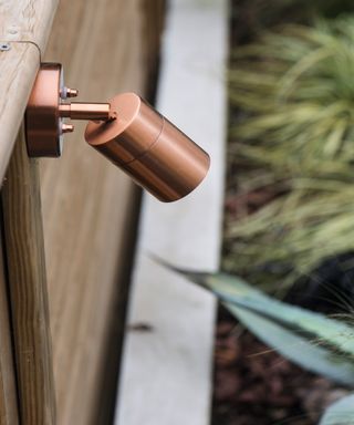 copper spotlight on timber fencing above raised planting beds