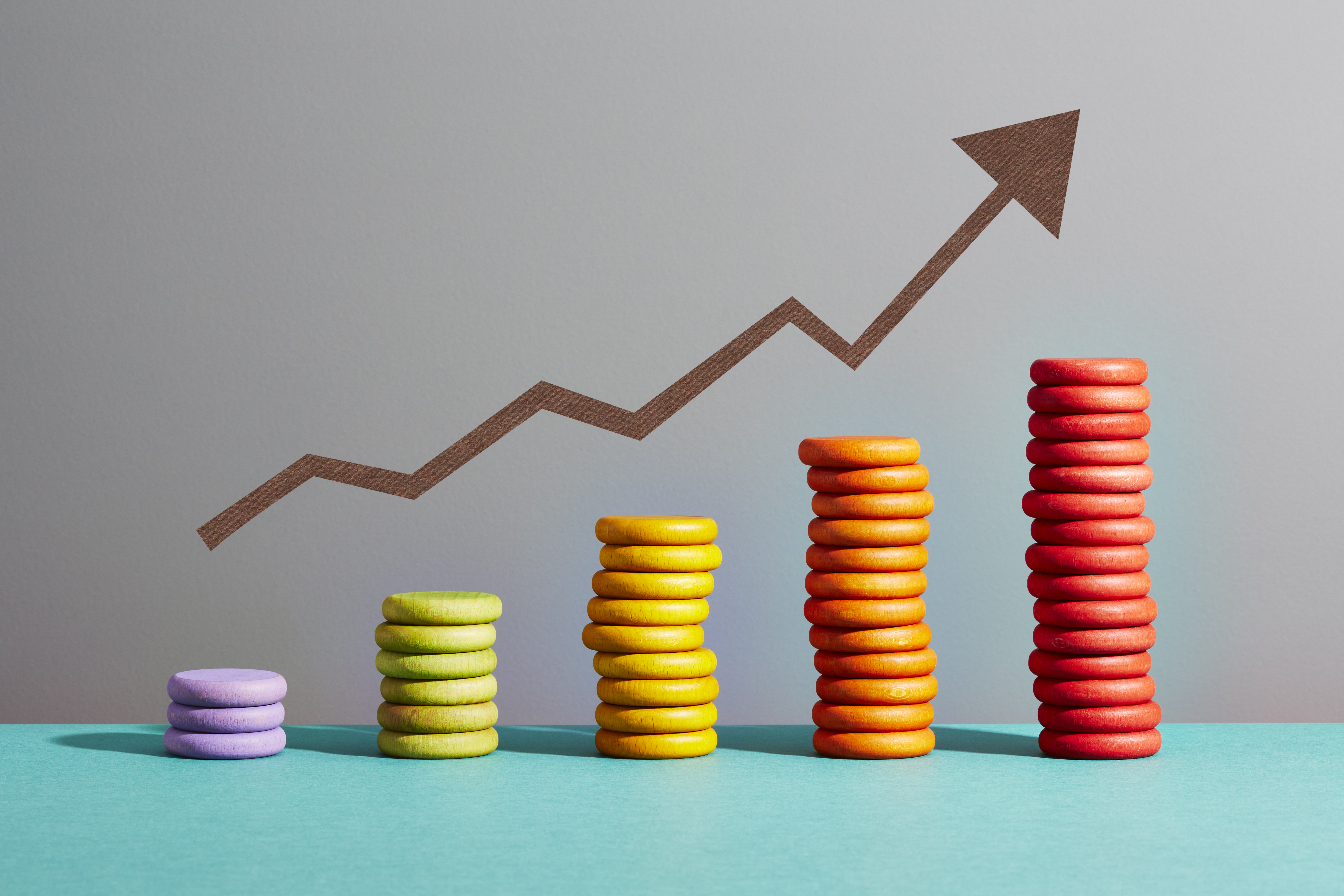 An arrow symbol above five stacks of coloured coins