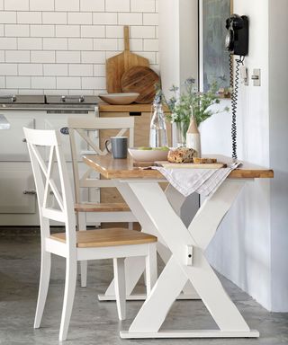 kitchen area with wooden dining table with white chair and white wall