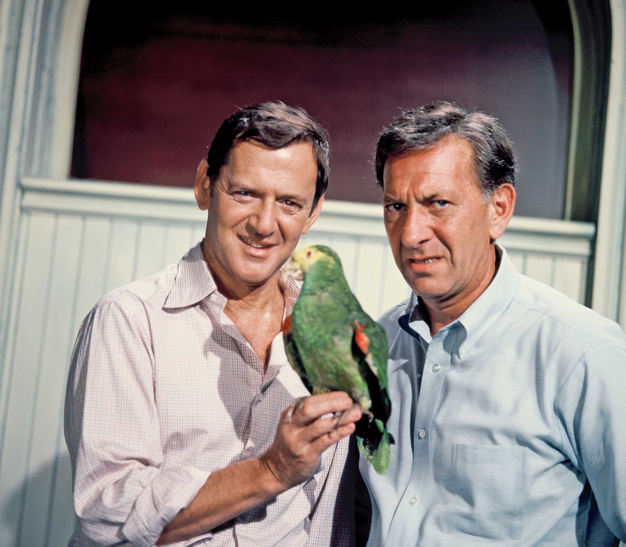 Felix Unger and Oscar Madison, characters in the Odd Couple 1970s TV show, hold a macaw. 