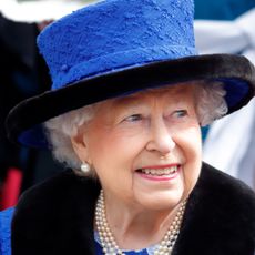 Queen Elizabeth in a bright blue hat smiling