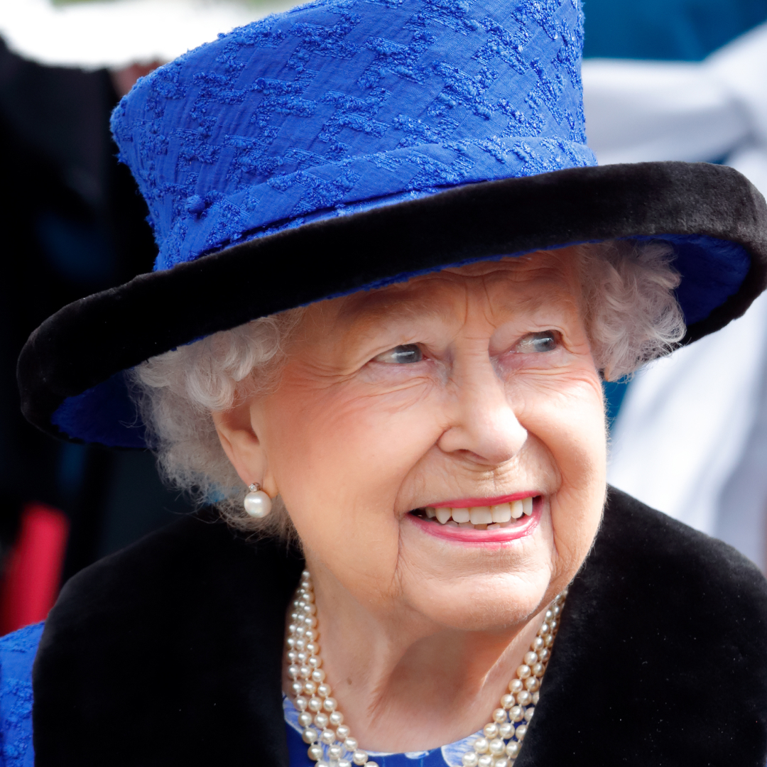 Queen Elizabeth in a bright blue hat smiling