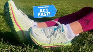 Hoka running shoe pictured worn from ankle down on grass with Act Fast badge