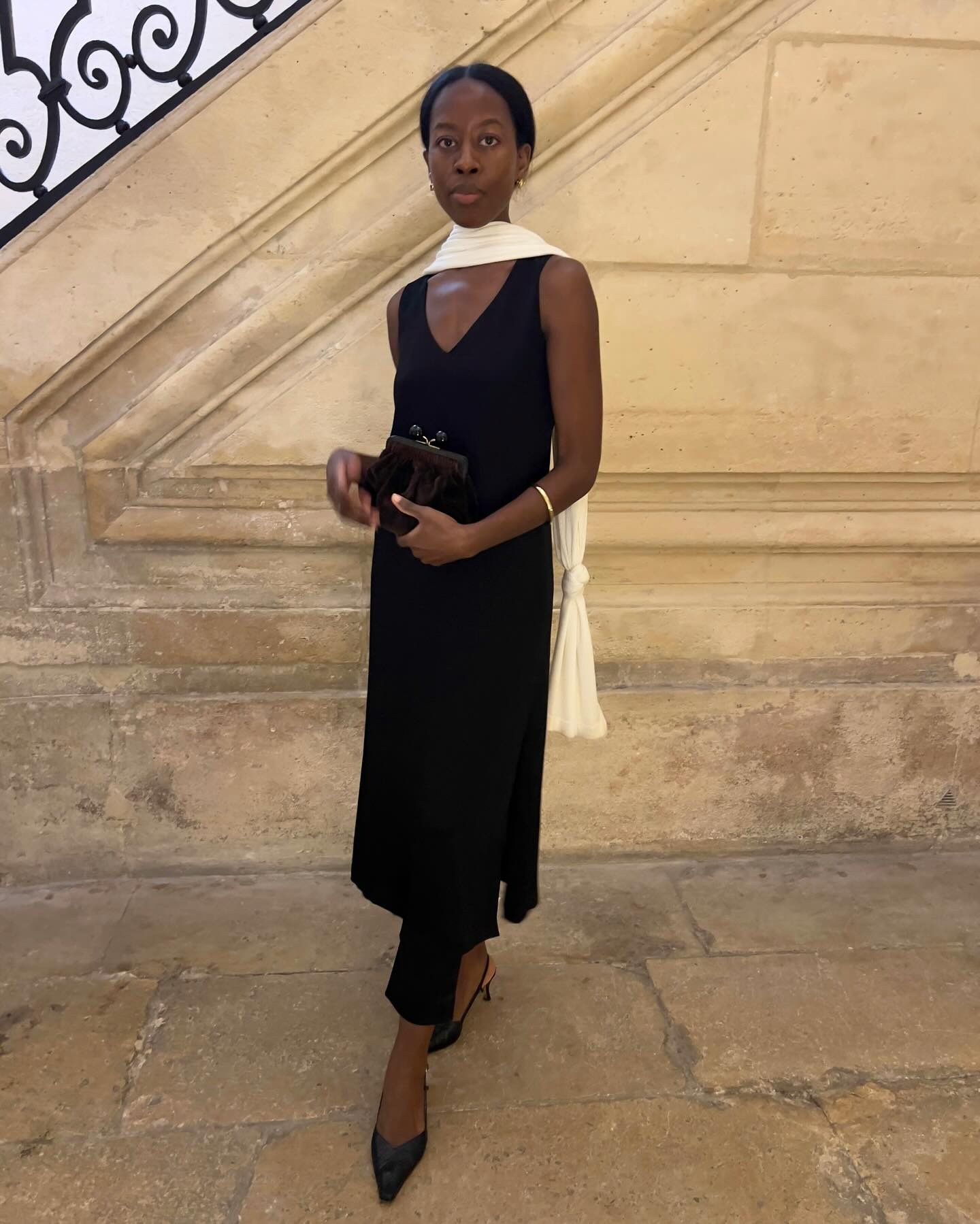 style influencer Sylvie Mus poses in a V-neck black midi dress with black slingback heels