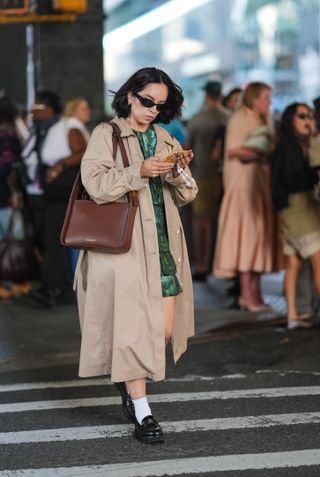 woman wearing trench coat, dress, loafers, and socks