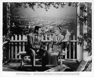 a couple sits on a bench over looking a city in the movie Perfect Strangers