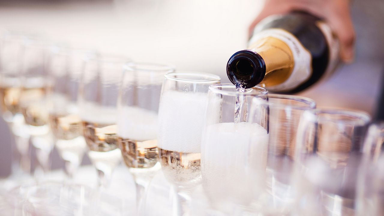 Waiter serving a glass of sparkling white wine