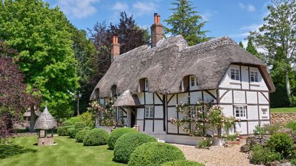 black and white thatched cottage with well in the garden