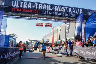 A runner coming across the finish line of the Ultra-Trail Australia with a banner