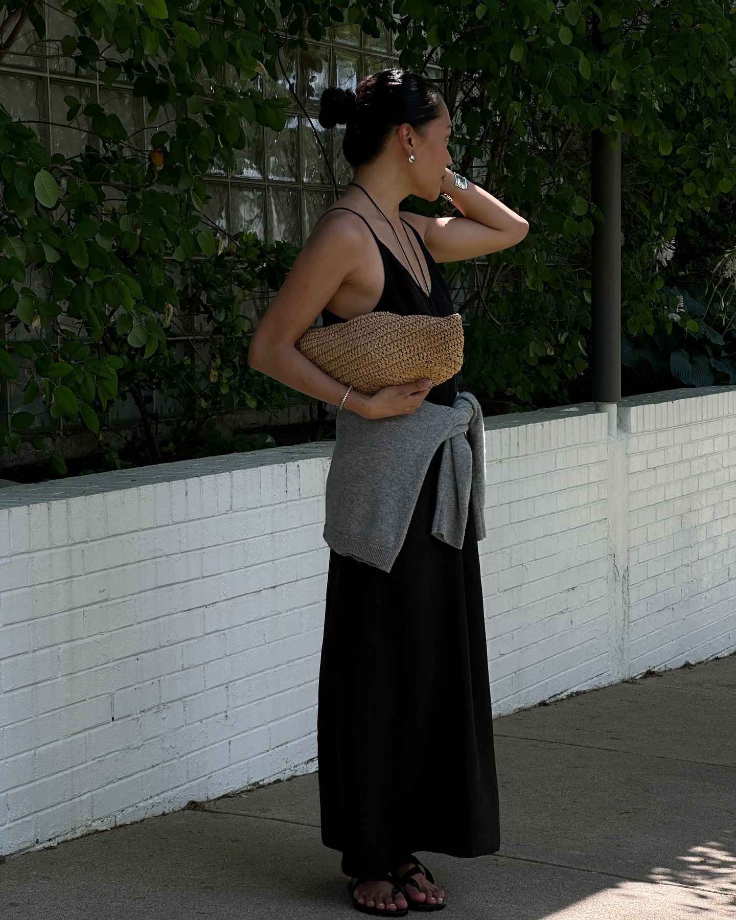 @dawn.tan wears a black slip dress with a grey jumper and a raffia bag