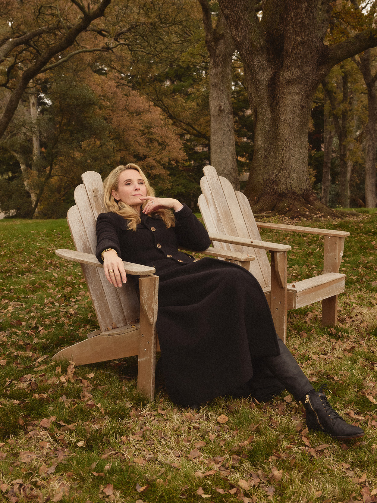 Jennifer Siebel Newsom sits on a wooden chair wearing a dark jacket and black boots in a photograph by Marie Claire
