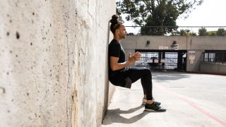 Man performs wall sit exercise outside