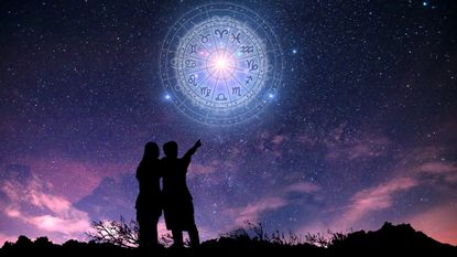 two people looking up at zodiac signs in the night sky