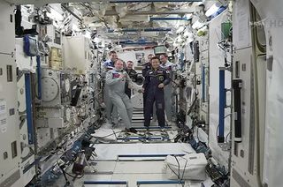 JAXA astronaut Koichi Wakata (at right) receives command of the International Space Station from Russian cosmonaut Oleg Kotov (left) during a brief ceremony held inside Japan's Kibo laboratory aboard the orbiting outpost on Sunday, March 9, 2014. Wakata i