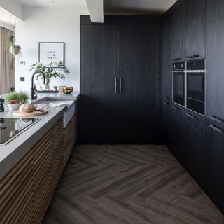 black kitchen with a wooden floor and wooden kitchen island