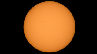 Mercury is photographed passing across the sun in the lower third of the image.