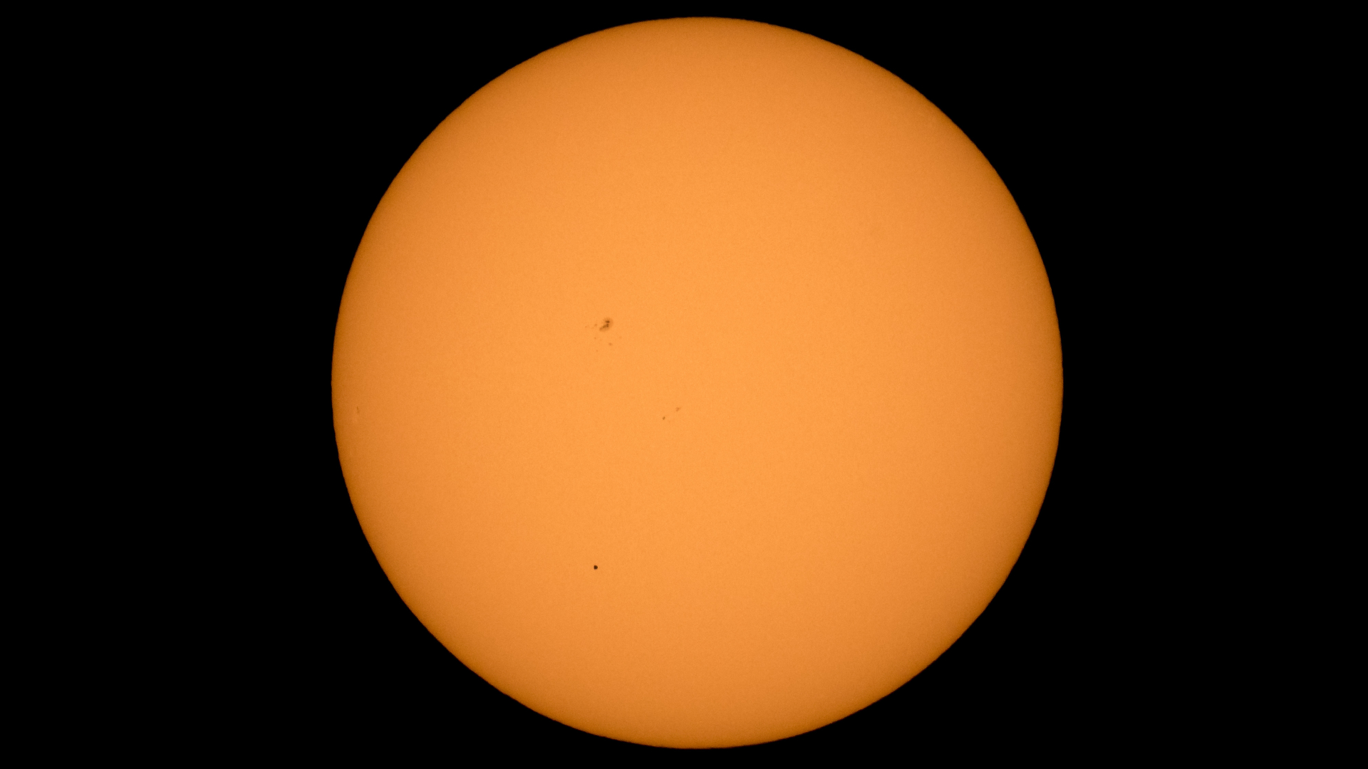 Mercury is photographed passing across the sun in the lower third of the image.