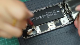 Close up view of technician using screwdriver to repair and replace battery of Apple iPhone
