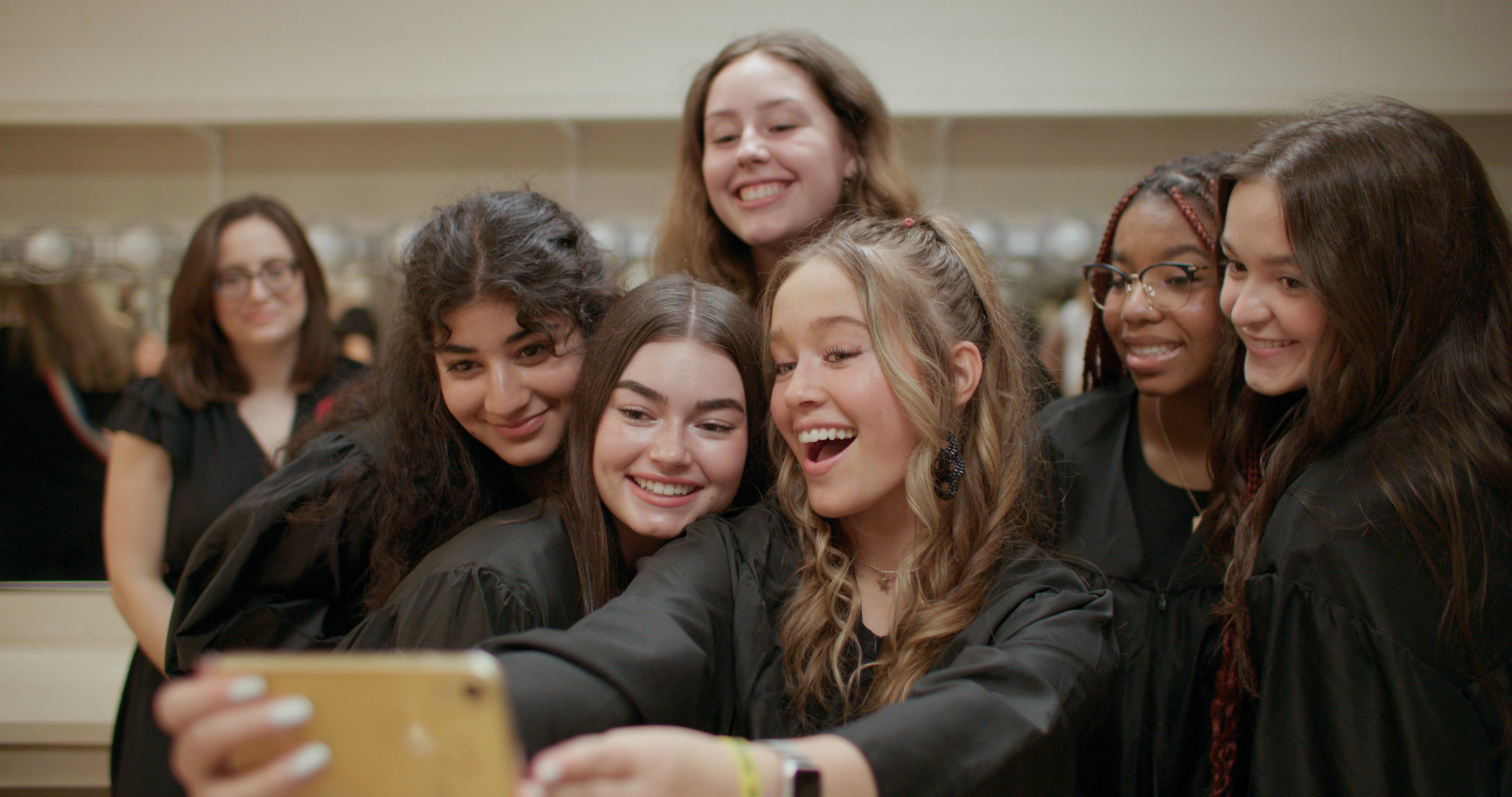 a group of girls dressed in black smile and pose for a selfie