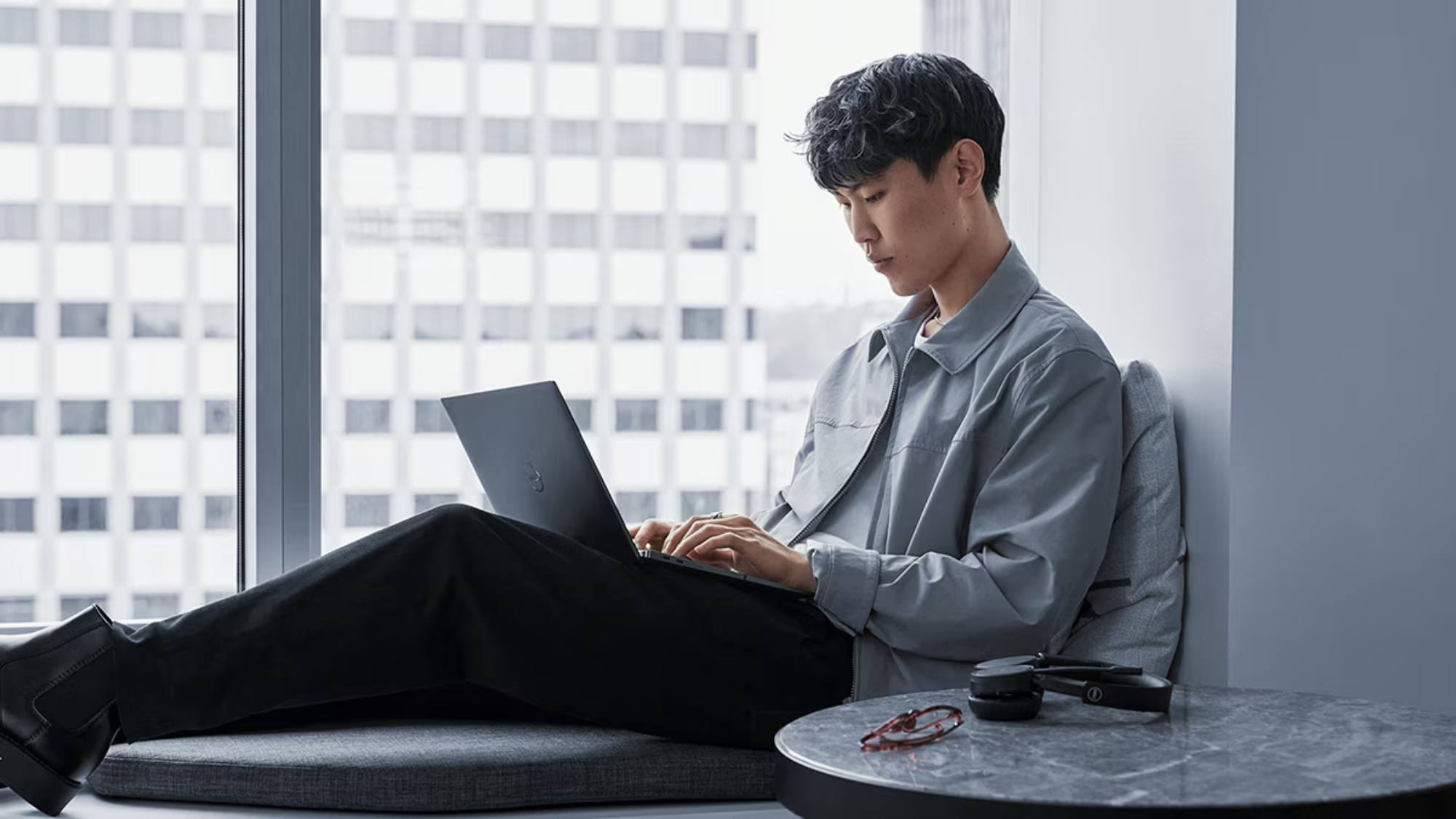 man using laptop on a windowsill