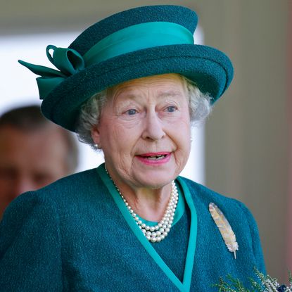 Queen Elizabeth wears a green suit and matching hat and Annie Leibovitz wears a black and gray jacket