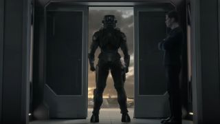 a futuristic soldier in armor stands in a doorway.