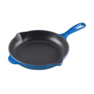 le creuset iron skillet in blue on a white background