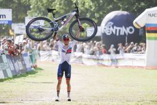 Thomas Pidcock from Great Britain celebrates winning by raising his bike into the air before crossing the finish line at the men's elite Cross-Country Mountain Bike World Championships at Val di Sole.