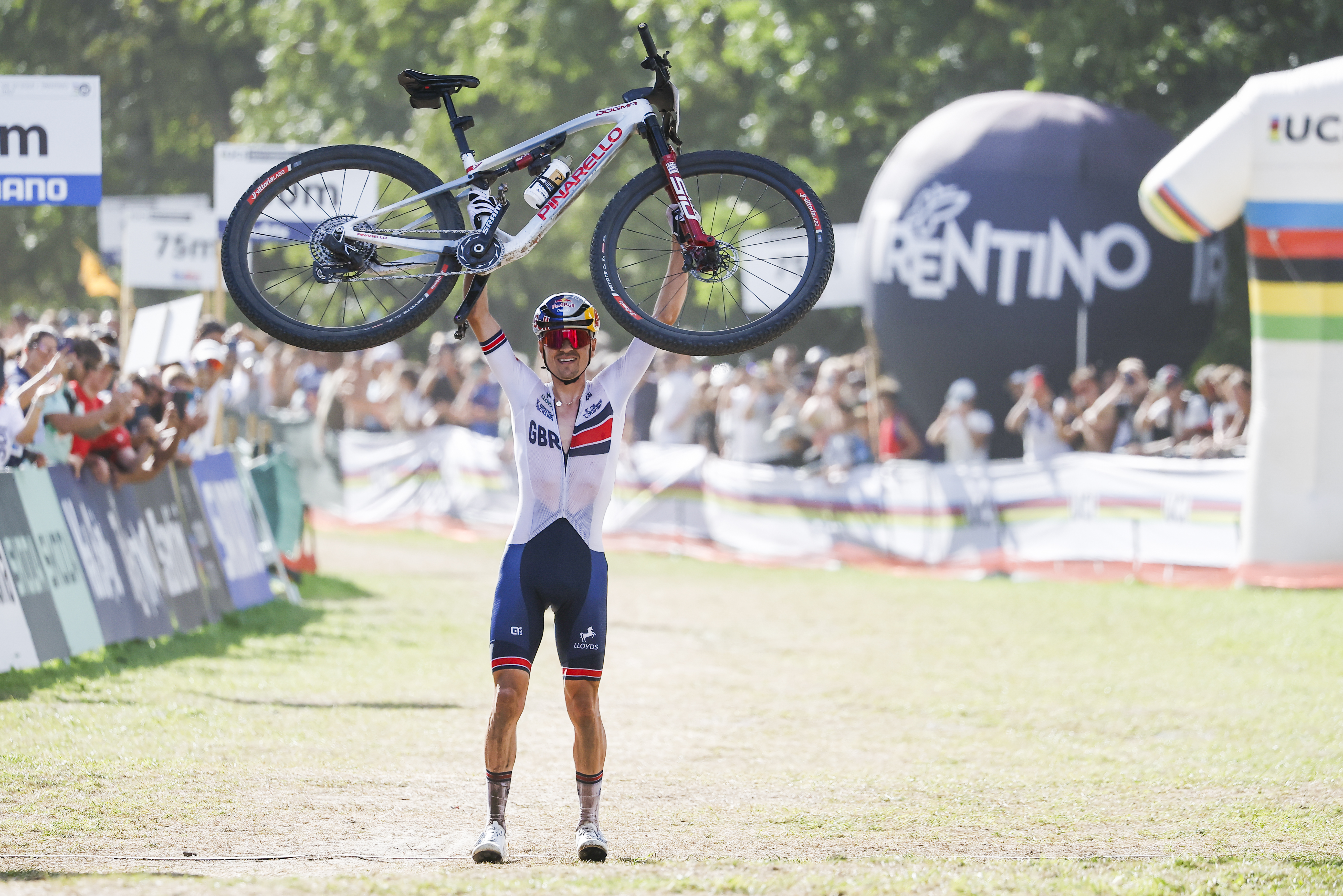 Thomas Pidcock from Great Britain celebrates winning by raising his bike into the air before crossing the finish line at the men's elite Cross-Country Mountain Bike World Championships at Val di Sole.
