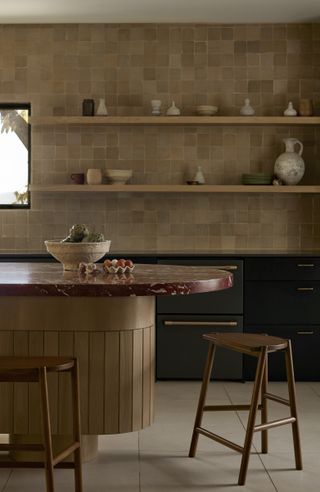 a black kitchen with beige zellige tiles