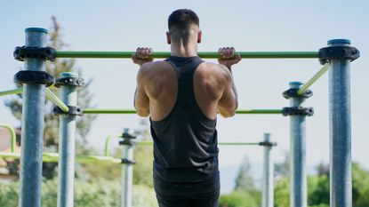 What to eat to build muscle after a workout: Image shows man doing pull ups outside