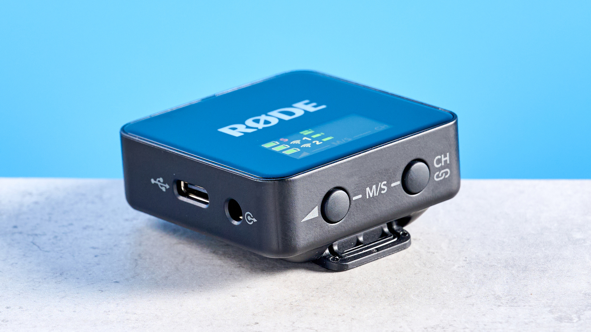 the rode wireless go gen 3 microphone with one receiver, two transmitters, shown against a blue background and with accessories like dead cat, charging ports, and cables