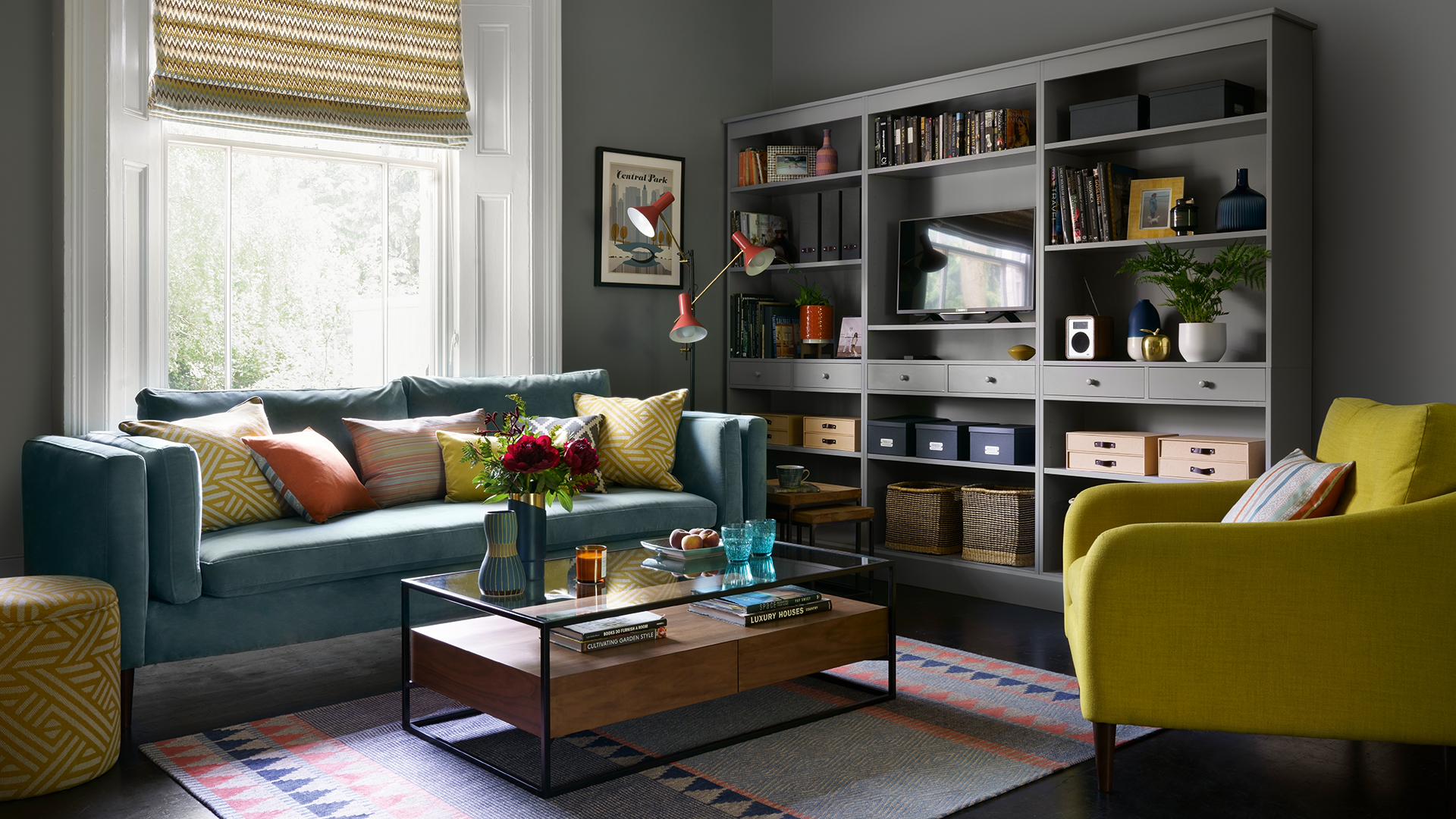 Dark grey living room with a teal velvet sofa lime green armchair and bespoke wall-mounted storage and tv unit