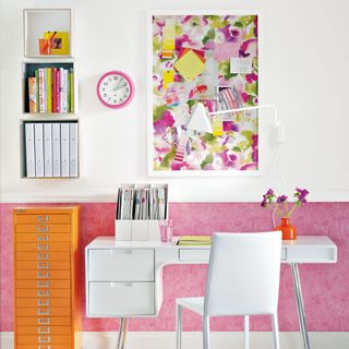 pink, white and yellow scheme with an orange filing cabinet pink wallpaper below the ado and a floral wallpapered pinboard