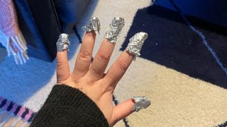 A shot of hands with nails wrapped with foil to show how to remove gel nails at home