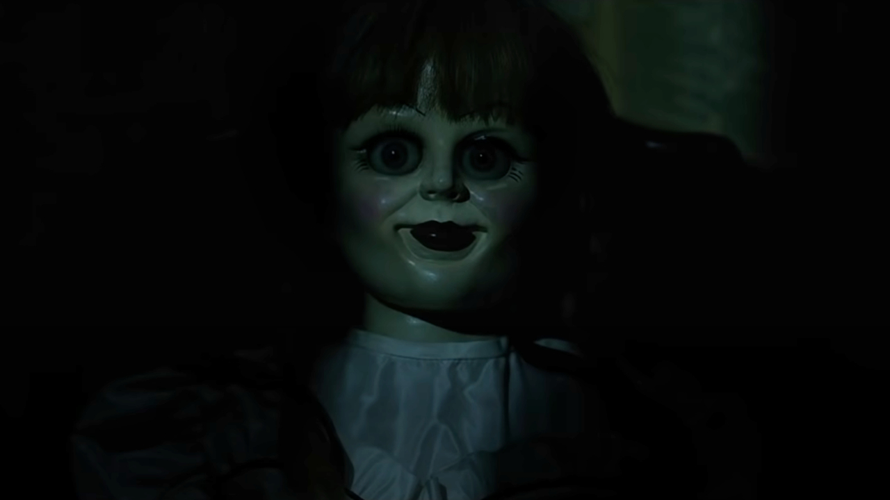 Annabelle the doll sits in a dark room, threateningly lit by moonlight in Annabelle: Creation.